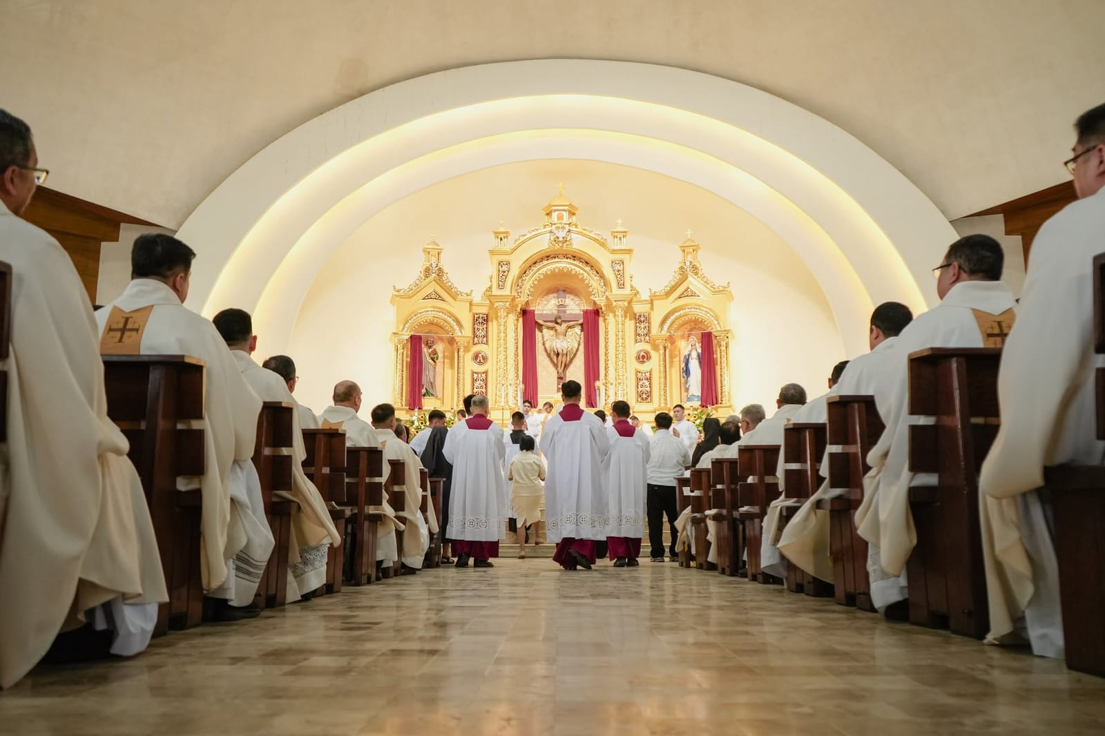 Clergy in procession down the centre aisle toward the golden altar